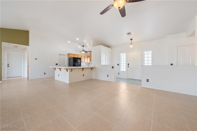 unfurnished living room featuring vaulted ceiling, visible vents, a ceiling fan, and light tile patterned floors