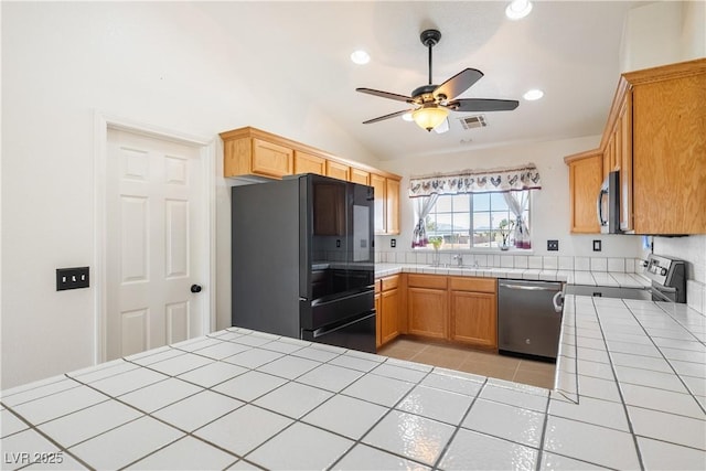 kitchen with visible vents, tile counters, lofted ceiling, ceiling fan, and stainless steel appliances