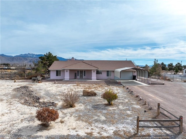 view of front of home featuring a tiled roof, fence, a porch, stucco siding, and a detached carport