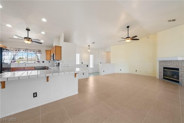 kitchen with visible vents, open floor plan, tile counters, and a ceiling fan