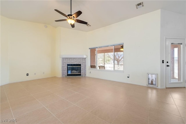 unfurnished living room with visible vents, ceiling fan, tile patterned floors, a fireplace, and high vaulted ceiling