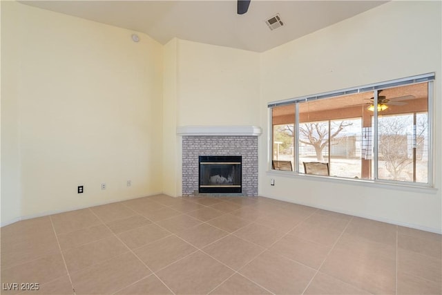 unfurnished living room with visible vents, ceiling fan, a fireplace, and light tile patterned floors