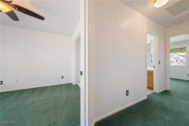 carpeted spare room featuring attic access, baseboards, and a ceiling fan