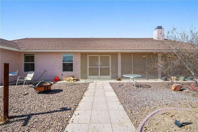 exterior space featuring a patio area, a chimney, and stucco siding