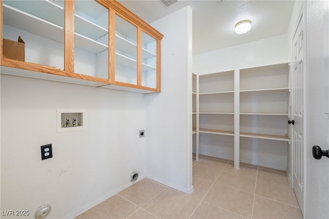 clothes washing area featuring light tile patterned flooring, hookup for an electric dryer, laundry area, washer hookup, and baseboards