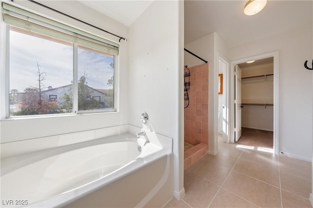 full bath with baseboards, tile patterned floors, a walk in closet, a shower stall, and a bath