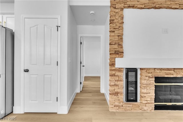 hallway featuring wine cooler, light wood-style flooring, and baseboards