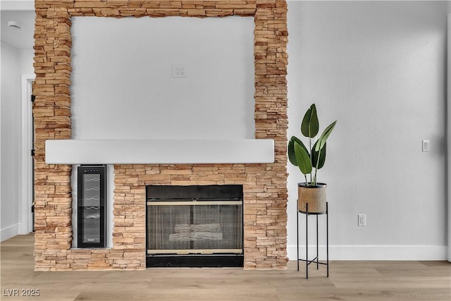 details with a stone fireplace, wood finished floors, and baseboards