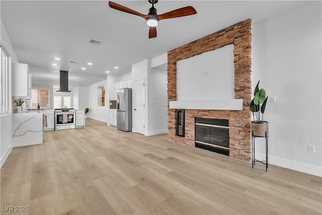 living area with light wood finished floors, baseboards, a fireplace, and visible vents