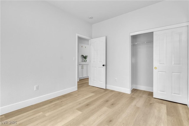 unfurnished bedroom with a closet, baseboards, and light wood finished floors