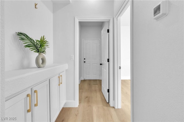 corridor featuring light wood-type flooring and baseboards