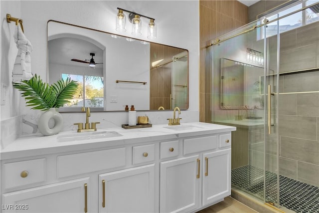 bathroom with double vanity, a shower stall, a ceiling fan, and a sink