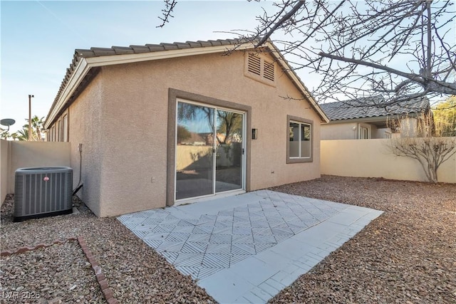 rear view of property featuring a patio, stucco siding, fence, cooling unit, and a tiled roof