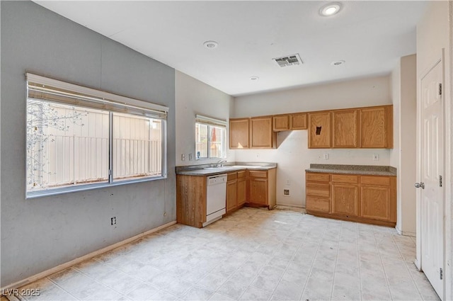 kitchen with brown cabinets, visible vents, white dishwasher, and a sink