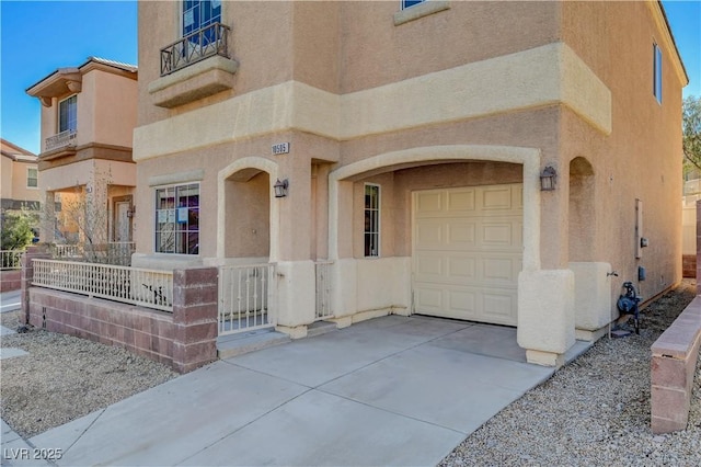 view of exterior entry with a garage, fence, concrete driveway, and stucco siding