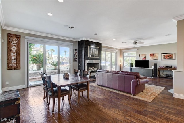 dining room with dark wood-style flooring, a fireplace, visible vents, baseboards, and ornamental molding