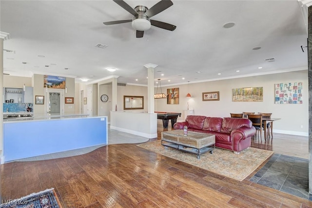 living area with ornamental molding, wood finished floors, decorative columns, and visible vents