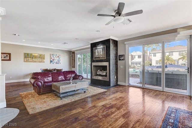 living area with dark wood finished floors, a fireplace, visible vents, ornamental molding, and baseboards