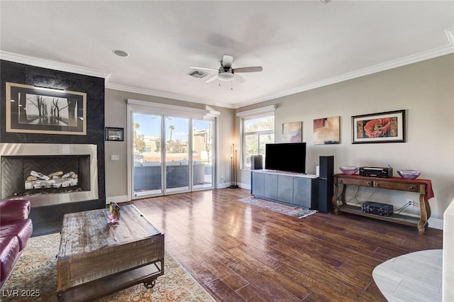 living room featuring a fireplace, visible vents, dark wood finished floors, and ornamental molding