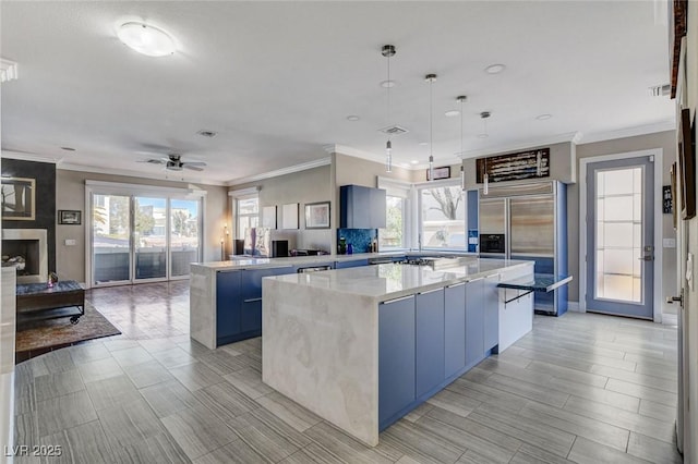 kitchen with built in fridge, blue cabinets, a kitchen island, open floor plan, and hanging light fixtures