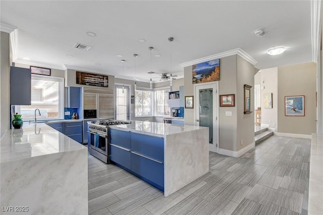 kitchen with range with two ovens, a center island, light stone counters, visible vents, and blue cabinets