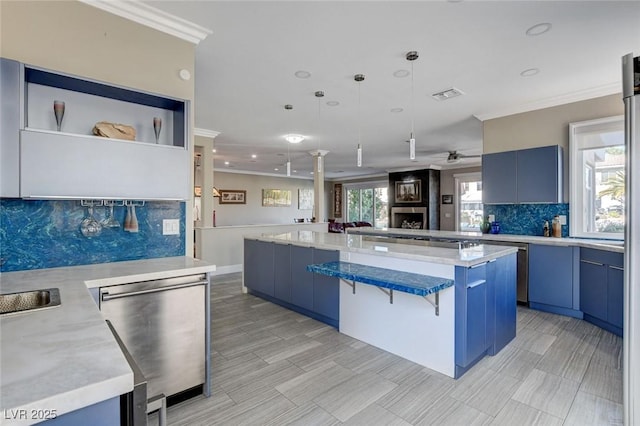 kitchen with blue cabinets, stainless steel dishwasher, a center island, a kitchen bar, and decorative light fixtures