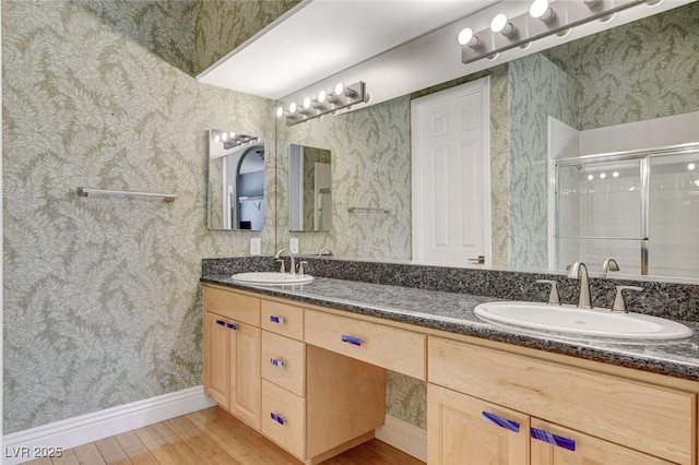 full bath with wood finished floors, a sink, a shower stall, and wallpapered walls