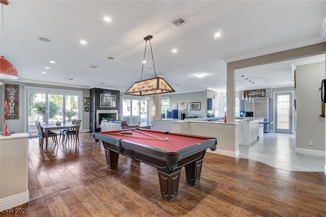 game room with ornamental molding, a healthy amount of sunlight, a fireplace, and wood finished floors