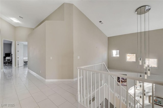 hall featuring baseboards, visible vents, an upstairs landing, and light tile patterned flooring