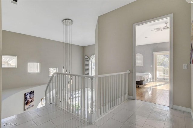 corridor featuring an upstairs landing and baseboards