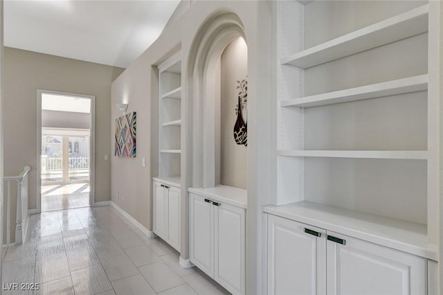 corridor featuring built in shelves and baseboards