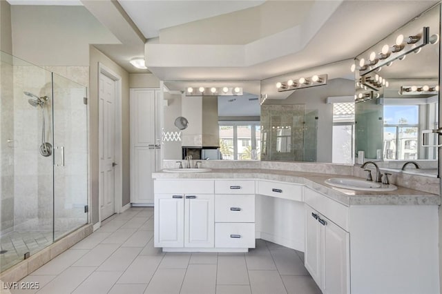 bathroom featuring a stall shower, tile patterned flooring, a sink, and double vanity