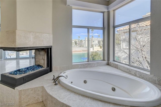 bathroom with a tile fireplace and a tub with jets