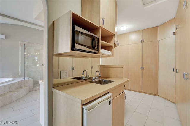 kitchen featuring open shelves, light countertops, stainless steel microwave, a sink, and dishwasher