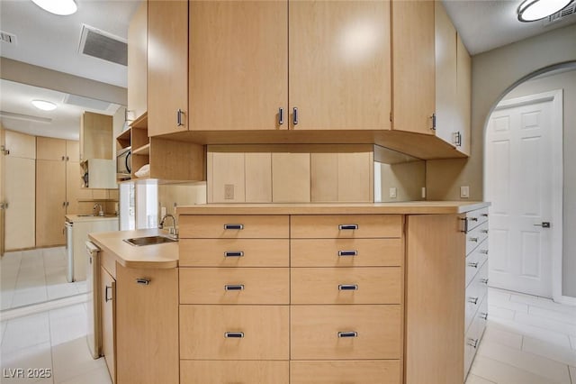 kitchen with light brown cabinets, a sink, visible vents, light countertops, and washing machine and clothes dryer