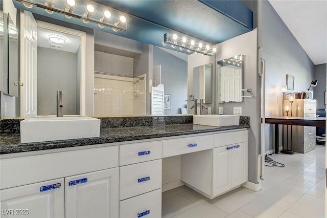 bathroom with vaulted ceiling, a tile shower, and vanity