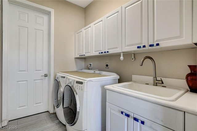 laundry room with washer and clothes dryer, a sink, cabinet space, and light wood-style floors