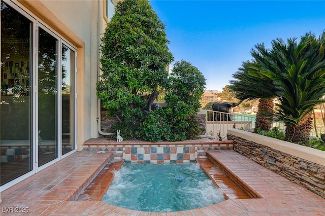 view of pool featuring a patio area, fence, and an in ground hot tub