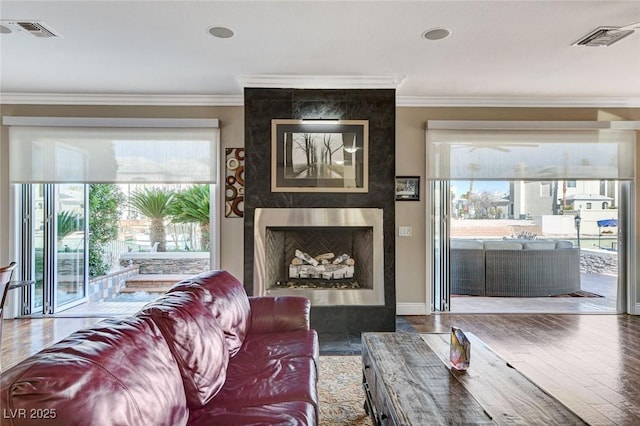 living area featuring visible vents, crown molding, and wood finished floors