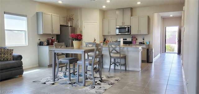7910 Shimmery St, North Las Vegas, NV 89084 - kitchen featuring stainless steel appliances, a kitchen island with sink, a kitchen bar, recessed lighting, and light tile patterned flooring