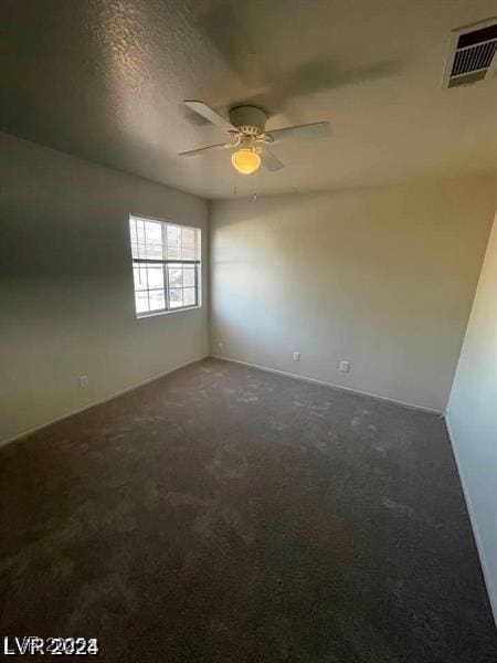 carpeted empty room with ceiling fan, a textured ceiling, and visible vents