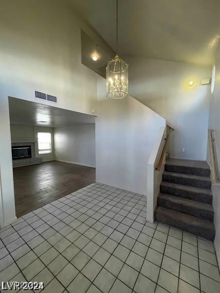 interior space featuring a fireplace, a notable chandelier, visible vents, stairway, and light tile patterned flooring