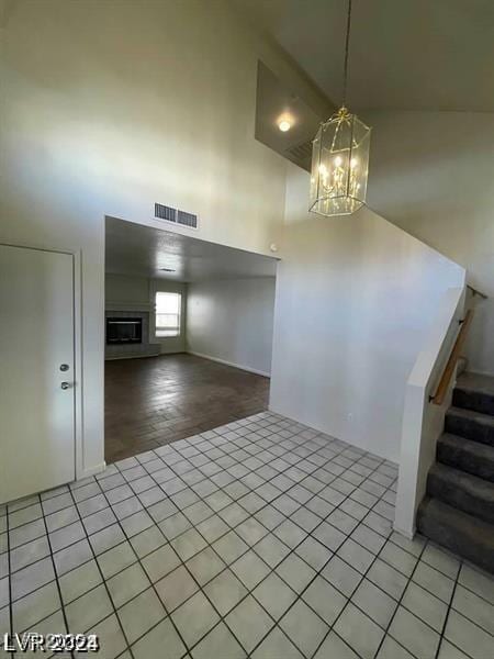 interior space with light tile patterned floors, visible vents, a towering ceiling, stairway, and a fireplace