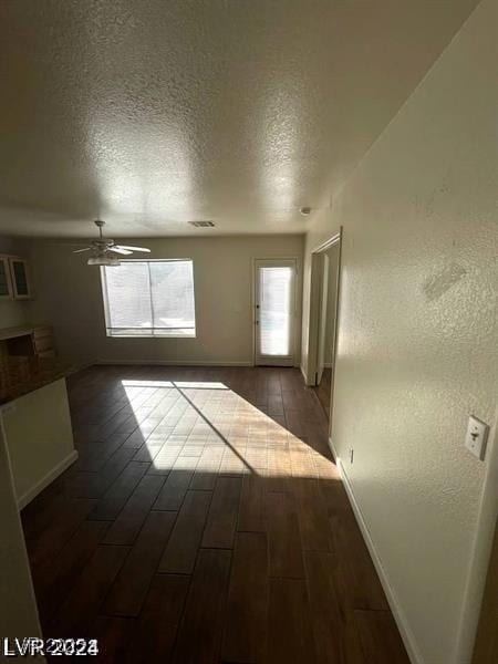 spare room with a healthy amount of sunlight, dark wood finished floors, a textured ceiling, and ceiling fan