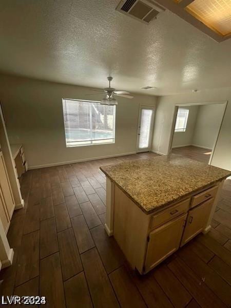 kitchen featuring ceiling fan, a kitchen island, visible vents, open floor plan, and wood tiled floor