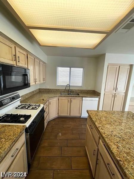 kitchen with light stone counters, white appliances, visible vents, and a sink