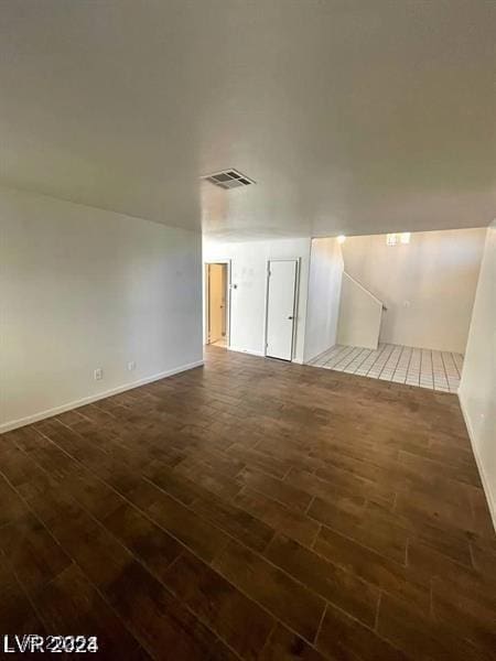 empty room featuring dark wood-style floors, visible vents, and baseboards