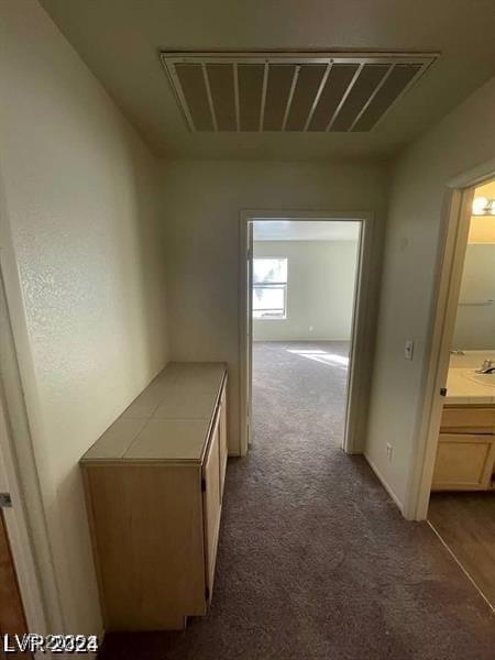 corridor with carpet floors, visible vents, and baseboards