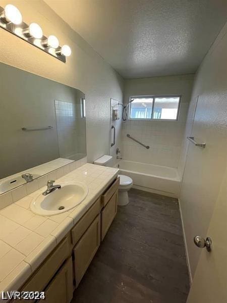 full bath featuring shower / bathtub combination, toilet, vanity, a textured ceiling, and wood finished floors