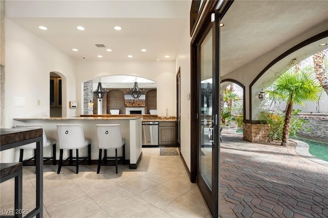 bar featuring light tile patterned floors, visible vents, arched walkways, pendant lighting, and recessed lighting